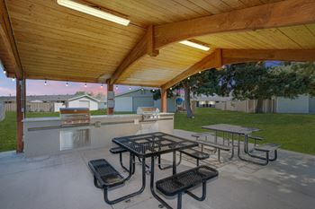A patio with picnic tables and a grill